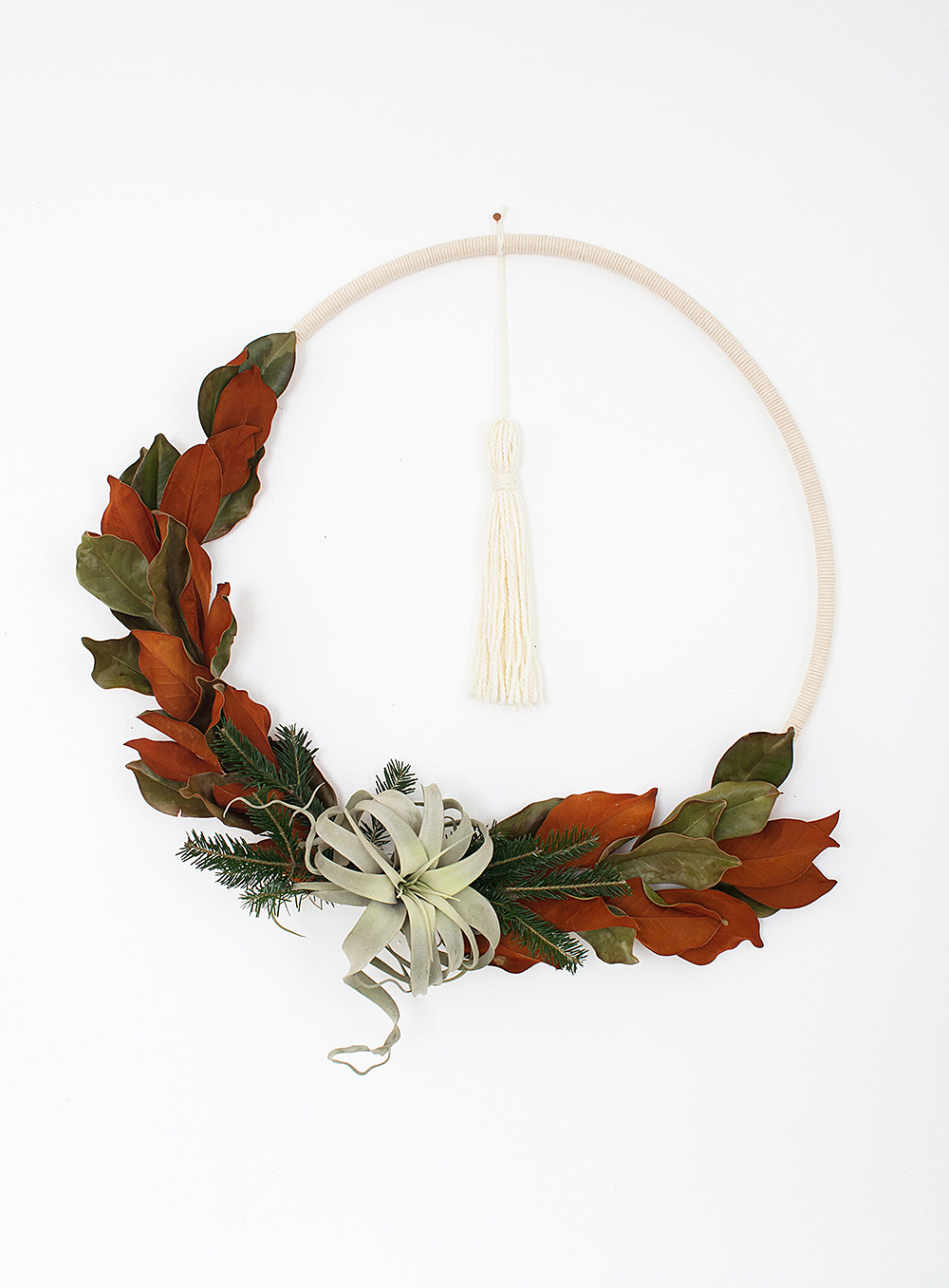 DIY Boho Winter Hula Hoop Wreath - Complete your modern Scandibo holiday decor with this simple yet stunning wreath made with fresh greens, cord, and an air plant!